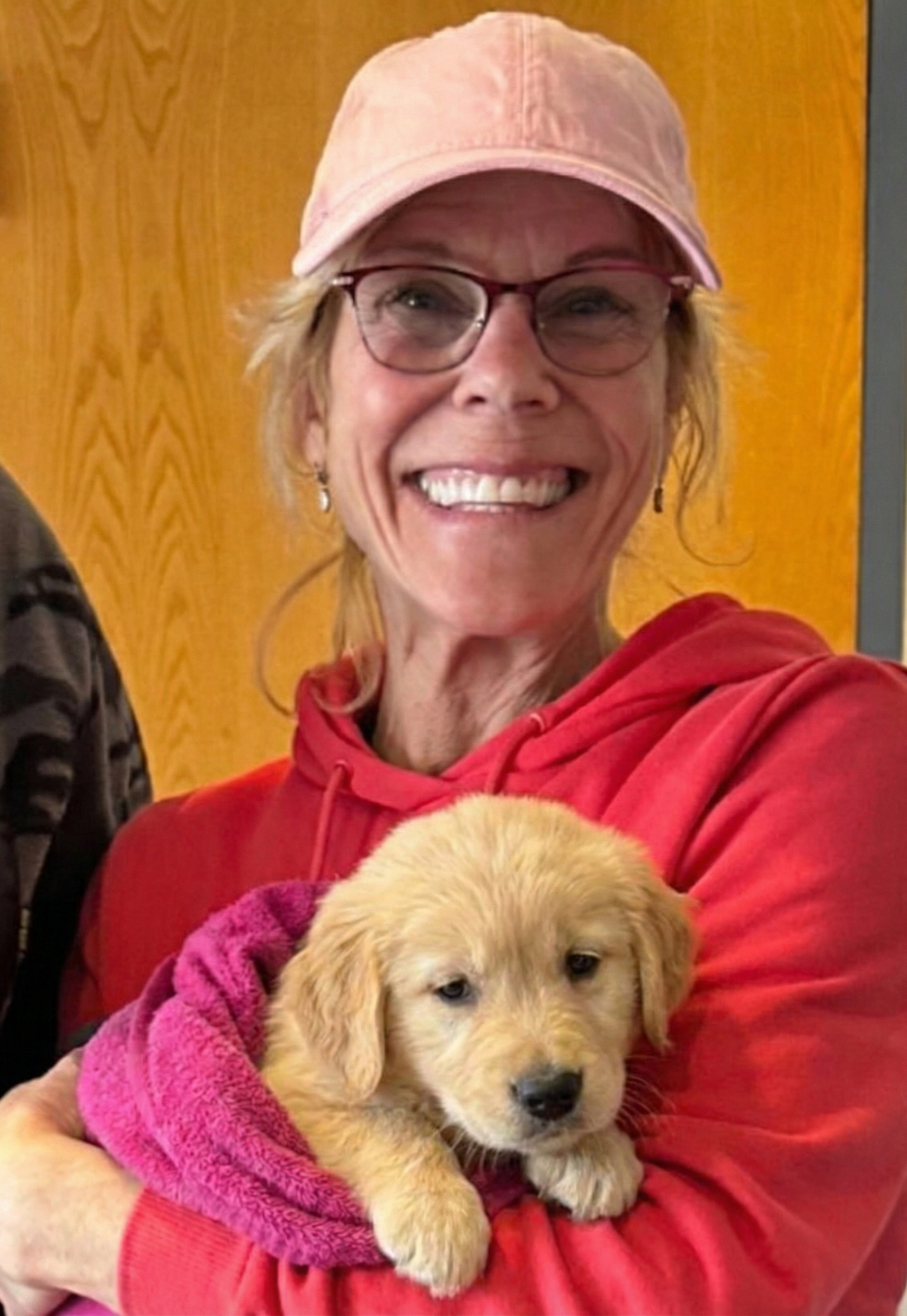 Christina, founder of Zakity, smiling and holding a golden retriever puppy wrapped in a pink towel